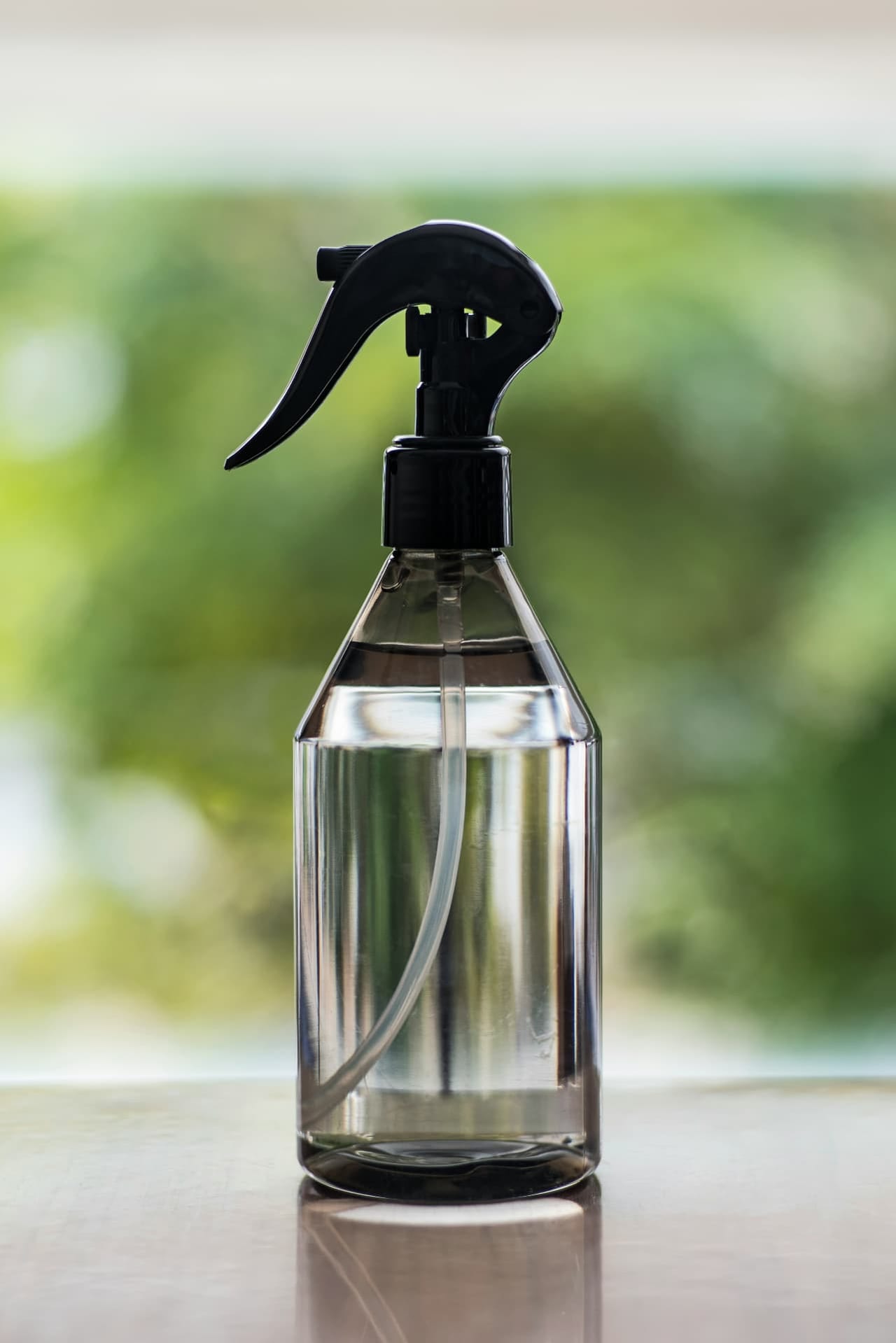 Person in Schutzanzug mit blauen Handschuhen hält eine Sprühflasche und ein Reinigungstuch